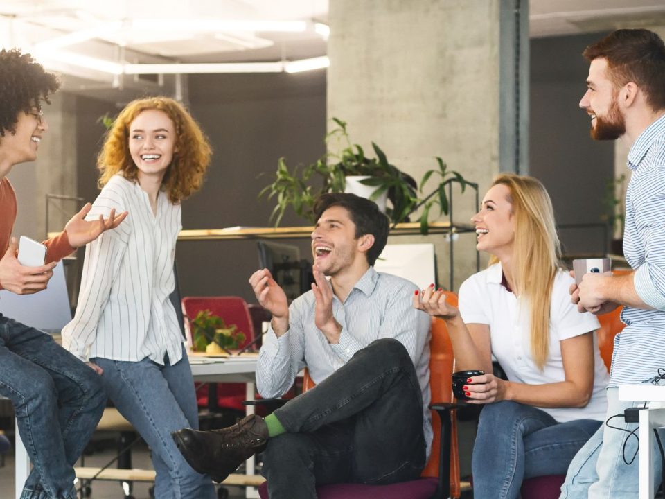 Fünf Kolleginnen und Kollegen unterhalten sich lachend in einem offenen Büro