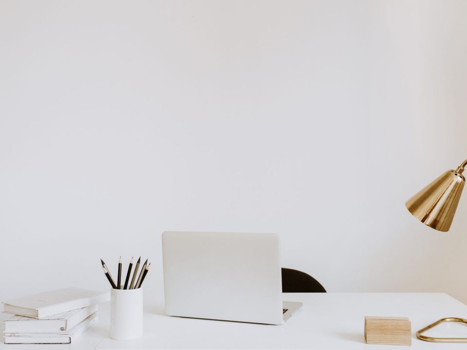 Aufgeräumter Einzelarbeitsplatz mit Laptop, Schreibtischlampe und Büchern
