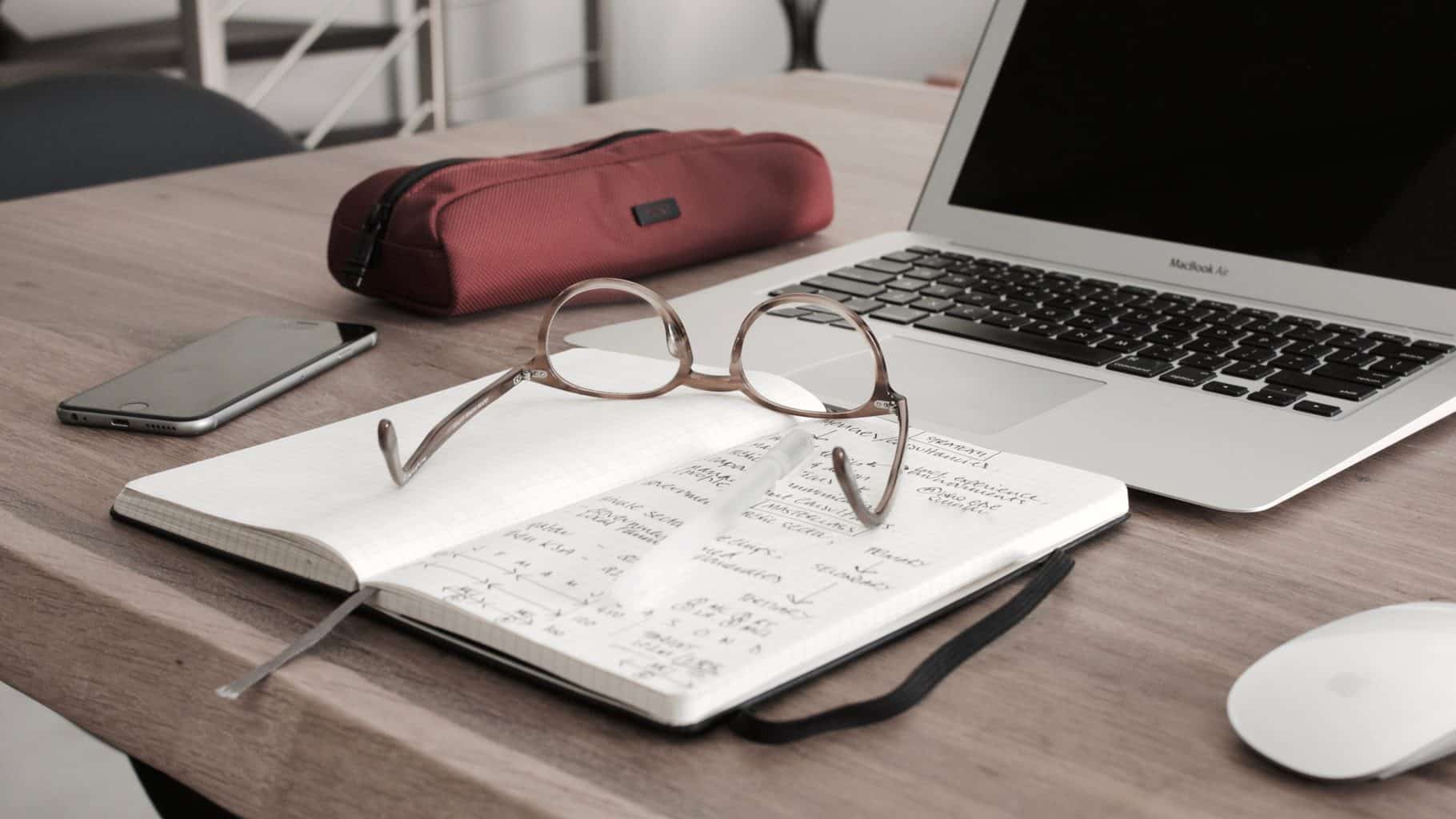 Brille auf Buch und Laptop